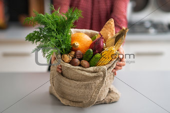 Closeup on young housewife showing fresh vegetables in shopping 