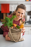 Portrait of smiling young housewife with vegetables from local m
