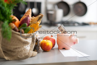 Closeup on money in piggy bank and purchases from local market o