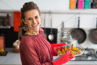 Portrait of happy young housewife holding baked pumpkin