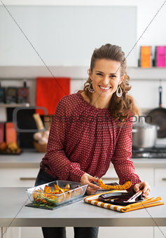 Happy young housewife serving baked pumpkin