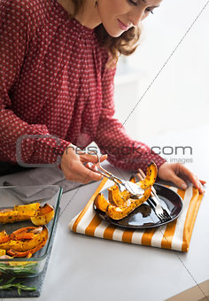 Closeup on young housewife serving baked pumpkin