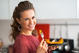 Portrait of young woman eating baked pumpkin in kitchen