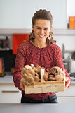 Happy young housewife showing basket with mushrooms