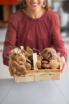 Closeup on young housewife showing basket with mushrooms