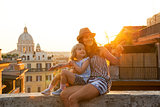 Mother and baby girl sitting on street overlooking rooftops of r