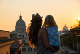 Silhouette of mother and baby girl looking on rooftops of rome o