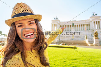Portrait of happy young woman pointing on piazza venezia in rome