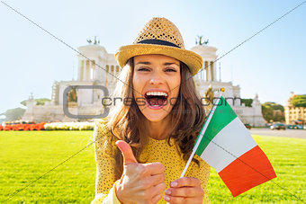 Portrait of happy young woman showing italian flag and thumbs up
