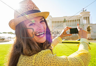 Portrait of happy young woman taking photo on piazza venezia in 
