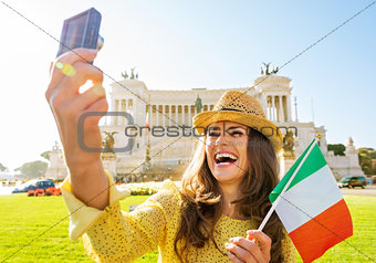 Happy young woman with italian flag making selfie on piazza vene
