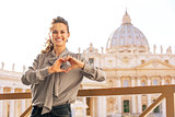 Happy young woman showing heart shaped hands in front of basilic