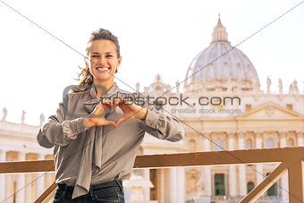 Happy young woman showing heart shaped hands in front of basilic
