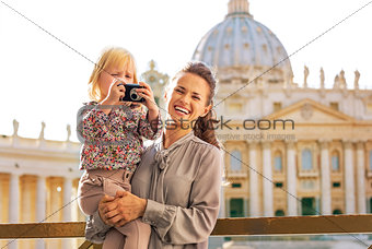 Happy mother and baby girl with photo camera on piazza san pietr