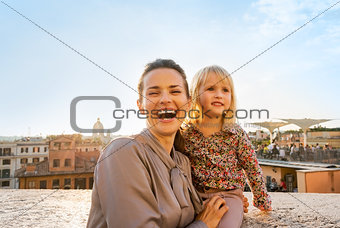 Portrait of happy mother and baby girl on street overlooking roo