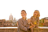 Mother and baby girl on street overlooking rooftops of rome on s