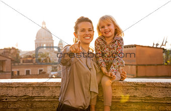 Happy mother and baby girl on street overlooking rooftops of rom