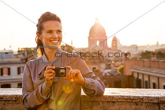 Happy young woman with photo camera on street overlooking roofto