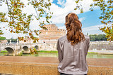 Young woman on embankment looking on castel sant'angelo in rome 