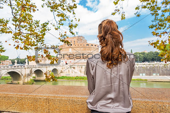 Young woman on embankment looking on castel sant'angelo in rome 