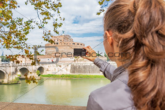 Young woman taking photo of castel sant'angelo in rome italy. re