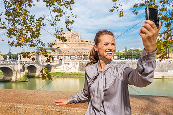 Smiling young woman making selfie on embankment near castel sant