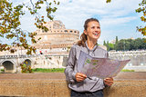 Portrait of happy young woman with map examining attractions on 