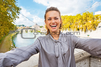 Smiling young woman making selfie on bridge ponte umberto I with