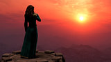 Woman Standing on Tower in Mountains at Sunset