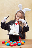 Happy magician girl conjuring up the easter bunny and eggs