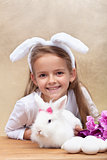 Happy little girl with bunny ears and her cute white rabbit