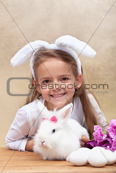 Happy little girl with bunny ears and her cute white rabbit