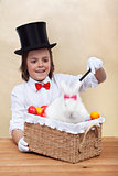 Happy magician boy conjuring an easter rabbit and colorful eggs