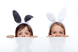 Kids with bunny ears peeking from beneath the table