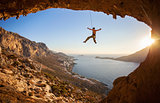 Rock climber hanging on rope while lead climbing at sunset