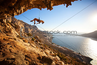 Female rock climber hanging on rope after unsuccessful attempt to take next handhold on cliff while lead climbin