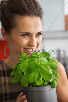 Portrait of happy young housewife with fresh basil