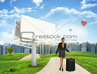 Businesswoman with suitcase on the road 