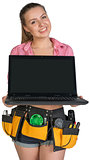 Woman in tool belt showing opened laptop with blank screen