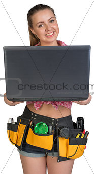 Woman in tool belt, holding opened laptop