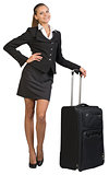 Businesswoman with wheeled travel bag, hand on hip