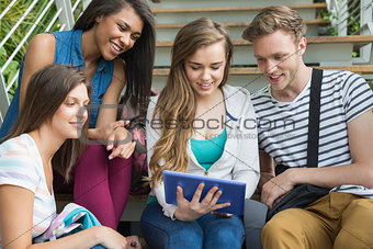 Smiling students sitting on steps with tablet pc