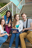 Smiling students sitting on steps with tablet pc