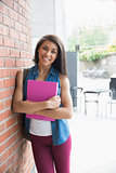 Pretty student smiling and holding notepads