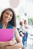 Pretty student smiling and holding notepads