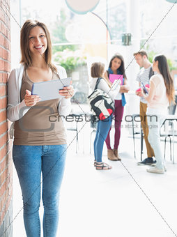 Pretty student smiling and holding tablet