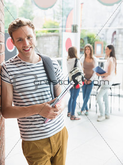 Handsome student smiling and holding notepads