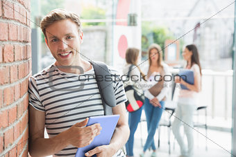 Handsome student smiling and holding tablet