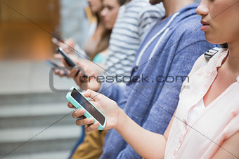 Students using their smartphones in a row