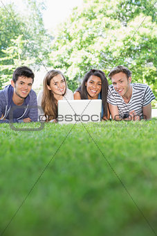 Happy students using laptop outside